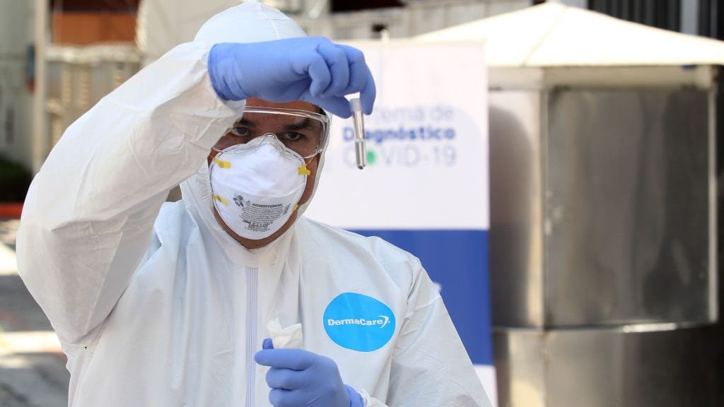 A health worker wearing a protective suit, prepares to take a CPR test on a driver showing symptoms suspected of being COVID-19, in Guadalajara, Mexico, on April 14, 2020. - The University of Guadalajara and the Health Sector of Jalisco started the "Radar Jalisco" programme with 12,000 CPR tests for people suspected of contracting Covid-19 in the state of Jalisco. (Photo by ULISES RUIZ / AFP) (Photo by ULISES RUIZ/AFP via Getty Images)