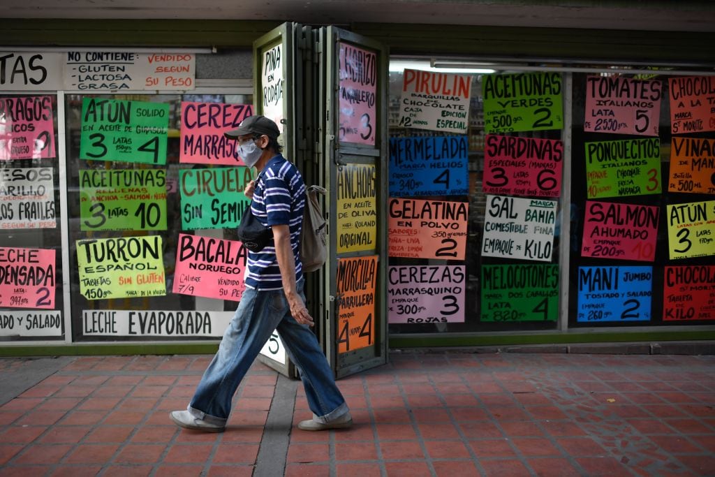Hombre camina ante un supermercado que vende sus productos en dólares en Caracas