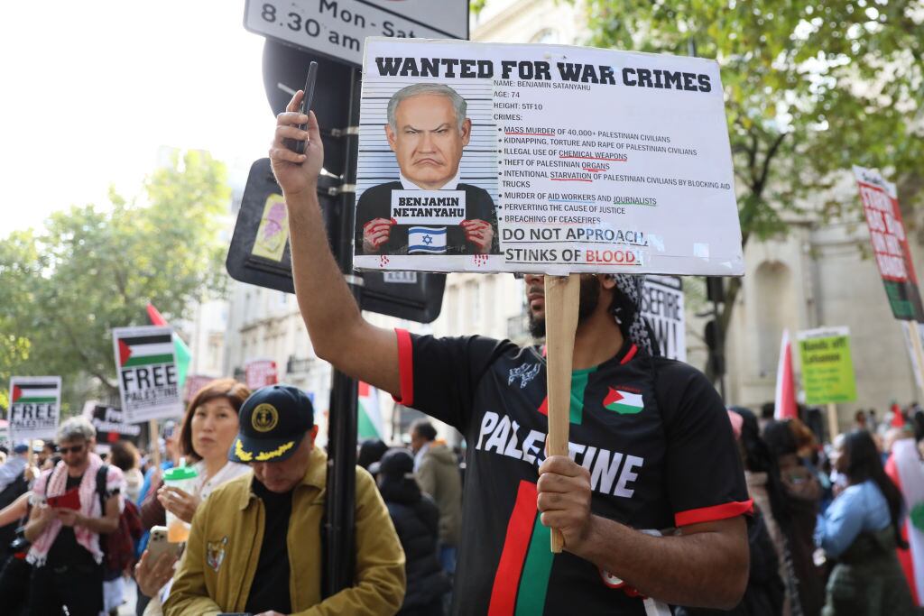 Manifestante porta un cartel que pide la detención de Benjamin Netanyahu por crímenes de guerra durante una manifestación en Londres de Inglaterra