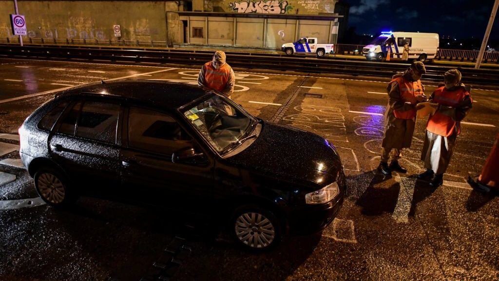 Argentine prefecture officials check a person's permit to circulate during a curfew early on April 9, 2021, at the Pueyrredon Bridge in Buenos Aires. - Argentina's President Alberto Fernandez announced a three-week overnight curfew on April 7, following a second consecutive day of record coronavirus infections. (Photo by RONALDO SCHEMIDT / AFP) (Photo by RONALDO SCHEMIDT/AFP via Getty Images)