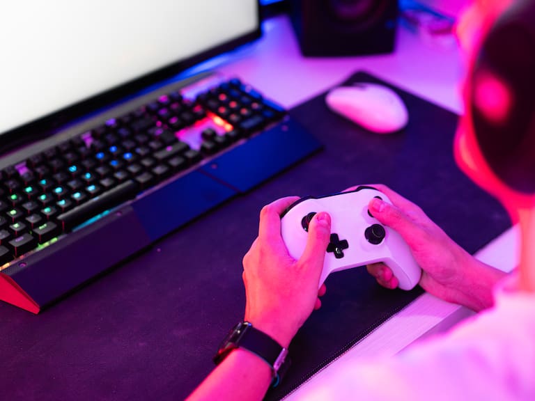 Gamer holding gamepad and playing video game on desktop