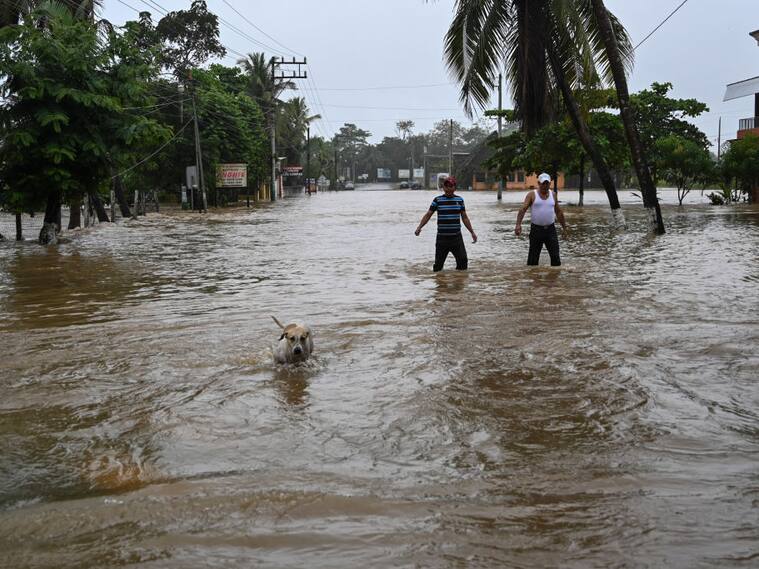 Dos personas caminan por una calle inundada en el municipio de Morales