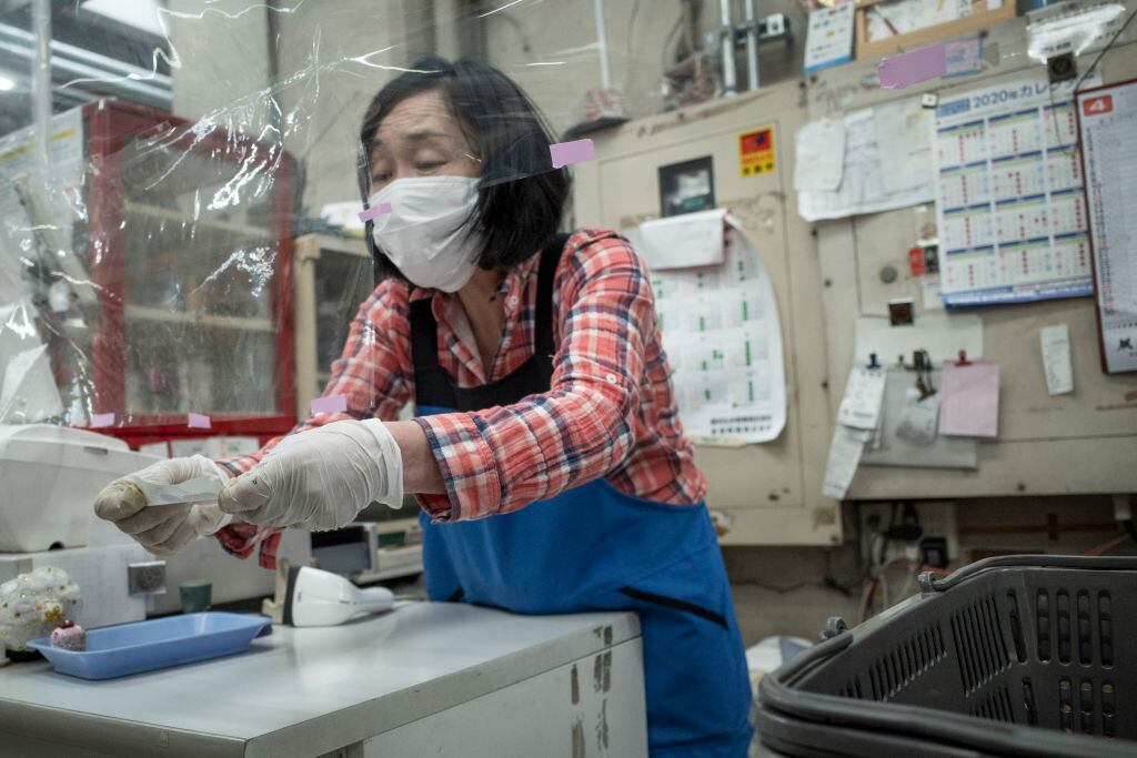 Una cajera utiliza medidas de seguridad para atender en Japón