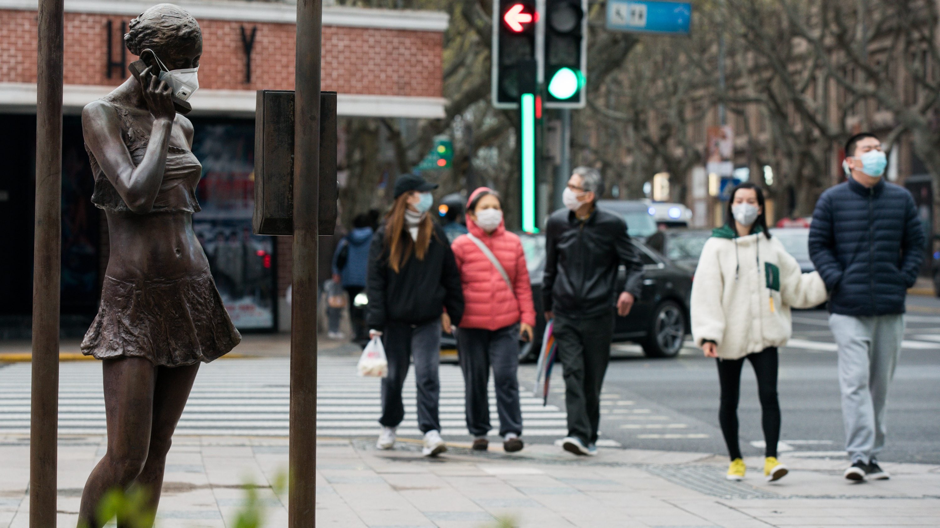 SHANGHAI, CHINA - MARCH 30: Pedestrians walk past a sculpture wearing a protective mask on March 30, 2020 in Shanghai, China. Health authorities of China said the country has passed the peak of the COVID-19 epidemic on March 12. As of today, the novel coronavirus (COVID-19) has infected more than 723,000 people and killed over 34,000 globally. The World Health Organization (WHO) declared the rapidly spreading coronavirus outbreak a pandemic on March 11. (Photo by Yves Dean/Getty Images)
