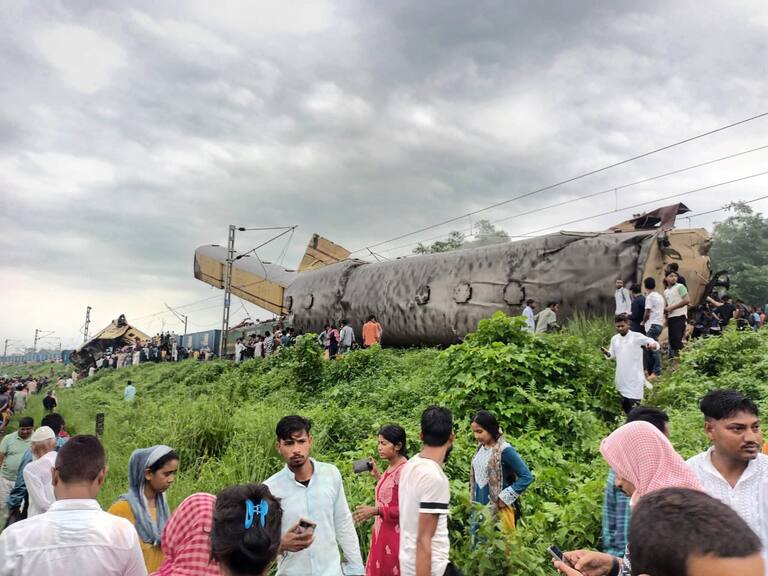 Personas observan los carros descarrilados cerca de una estación del distrito de Daarjeling de Bengala Occidental en la India.