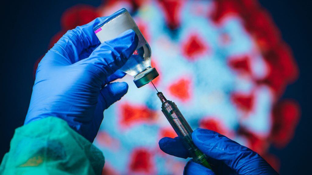 Coronavirus Covid-19 Protection and Vaccine. Doctor drawing up solution from vaccine bottle and filling syringe injection for patient vaccination in medical clinic, Coronavirus in background