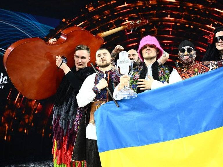 Members of the band &quot;Kalush Orchestra&quot; pose onstage with the winner&#039;s trophy and Ukraine&#039;s flags after winning on behalf of Ukraine the Eurovision Song contest 2022 on May 14, 2022 at the Pala Alpitour venue in Turin. (Photo by Marco BERTORELLO / AFP) (Photo by MARCO BERTORELLO/AFP via Getty Images)