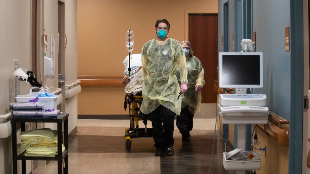 JAMESTOWN, ND - NOVEMBER 22: Kevin Bousquet, Jamestown Area Ambulance EMT wheels out a patient inside the emergency department at Jamestown Regional Medical Center, on Sunday, Nov. 22, 2020 in Jamestown, ND. In the course of a day, the ER staff had seen 29 patients, including five with COVID-19. They had also treated a cat bite, lacerations, bruises from domestic violence, an ankle injury and a dislocated shoulder. At the end of the 12-hour shift, hospital staff wheeled a COVID patient out of the double doors and loaded him into an ambulance. Hes got a lot of medical issues, Nikole Hoggarth, RN said. Hes from a nursing home. The night he came in here we put him on a BiPap, she said, referring to a machine that helps breathing. Jamestown Regional Medical Center had done all it could for them man. The ambulance departed on a 100-mile trip east to Fargo, a bigger hospital. (Francine Orr / Los Angeles Times via Getty Images)