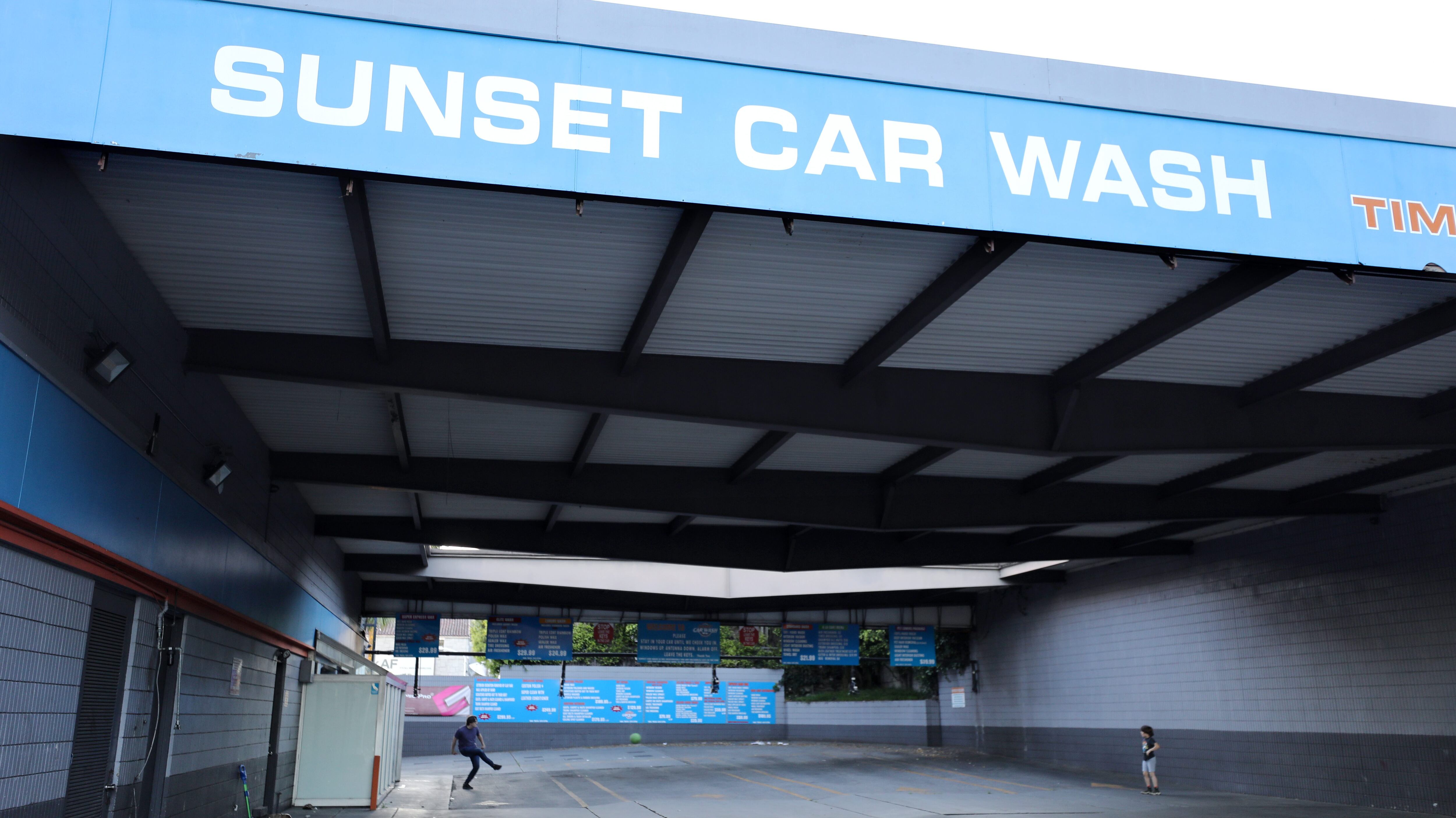 LOS ANGELES, CALIFORNIA  - APRIL 15:  A man and boy play soccer in a car wash which is currently shuttered due to the coronavirus pandemic on April 15, 2020 in Los Angeles, California. The man said they have begun to play there because some nearby parks have been closed due to the spread of COVID-19. (Photo by Mario Tama/Getty Images)
