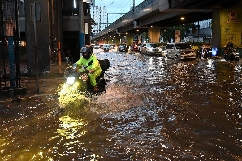 Motocicleta avanza por el agua de las calles inundadas en Filipinas