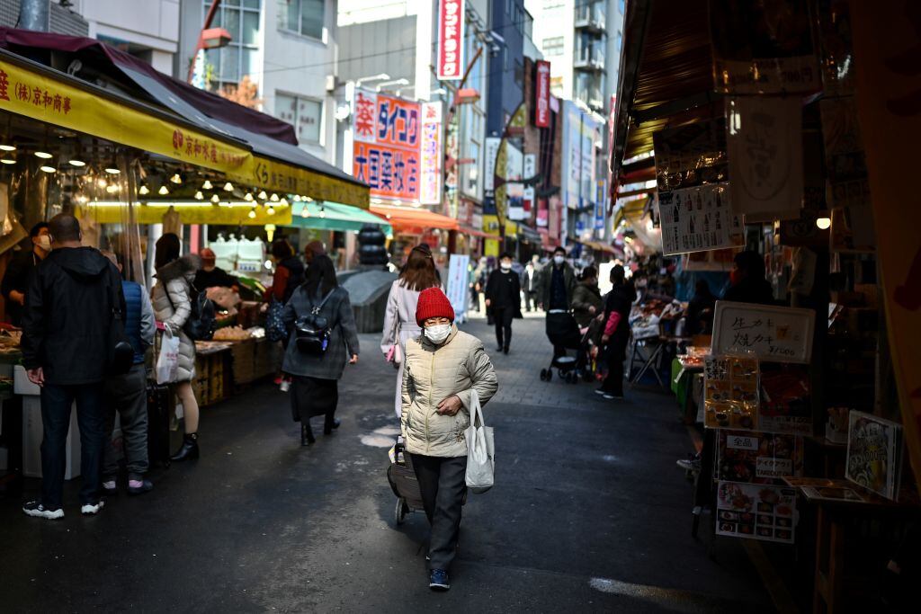 Una mujer con mascarilla camina por un mercado de Japón