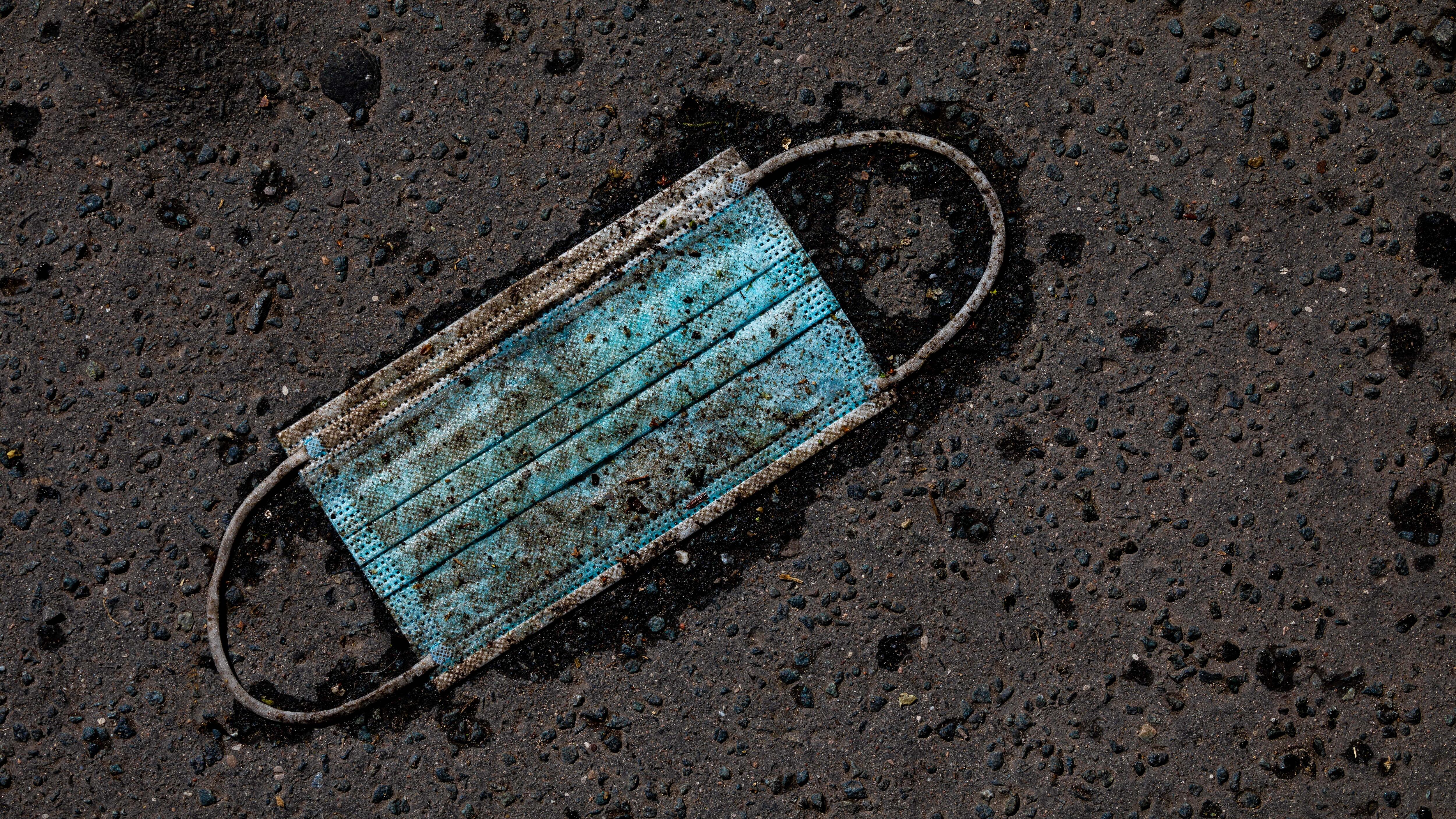 06 April 2021, Lower Saxony, Hanover: A heavily soiled medical mask lies on the asphalt. Photo: Moritz Frankenberg/dpa (Photo by Moritz Frankenberg/picture alliance via Getty Images)
