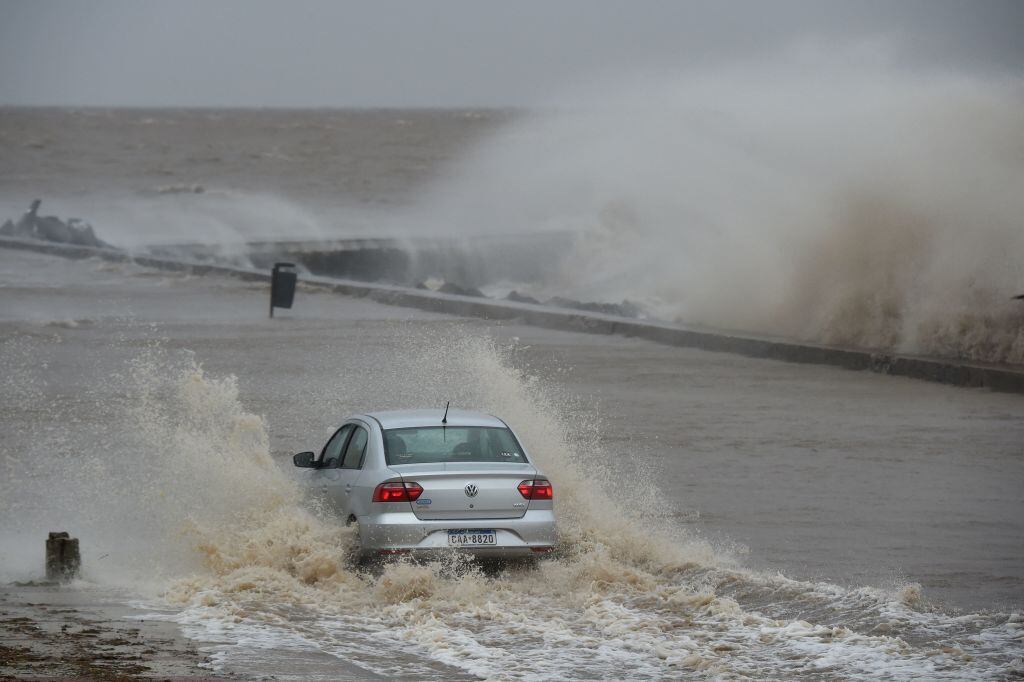 Un auto avanza en medio del agua que cubre una calle de Montevideo