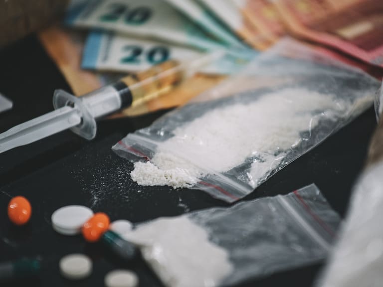 drugs in the form of powder and tablets, spoon and syringe on a black background