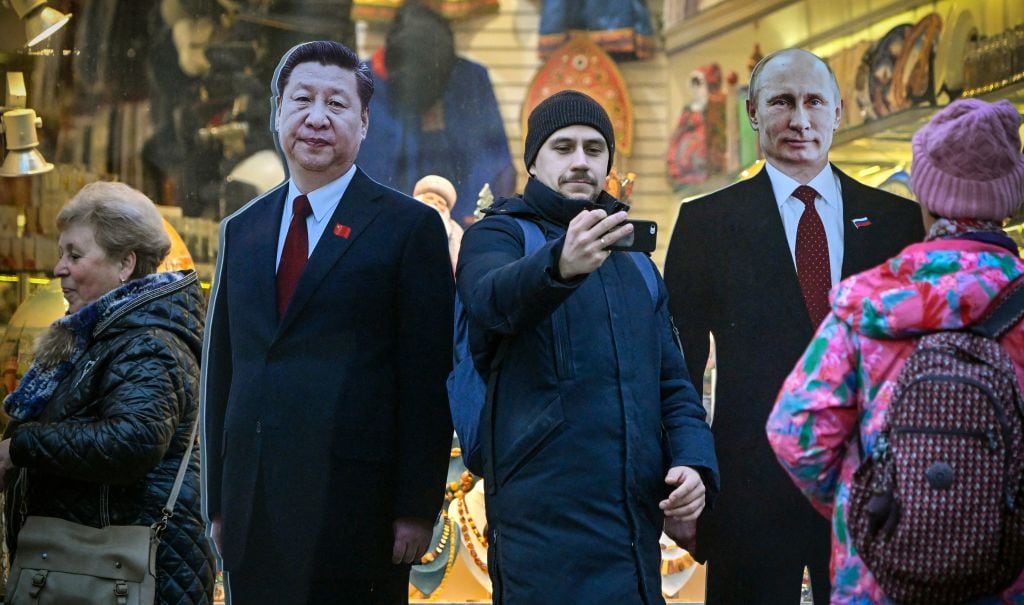 Un hombre en la ciudad de Moscú se saca una fotografía con dos retratos de cartón de los presidentes chino Xi Jinping y ruso Vladimir Putin.