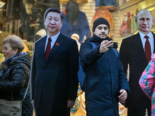 Un hombre en la ciudad de Moscú se saca una fotografía con dos retratos de cartón de los presidentes chino Xi Jinping y ruso Vladimir Putin.