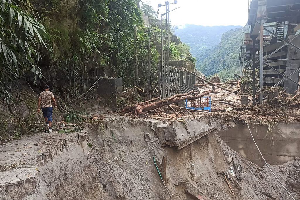 Hombre mira un camino destruido tras las graves inundaciones en India