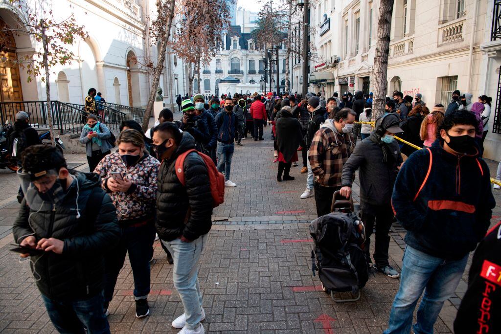 People wear face masks while queueing to enter a branch of the Pension Fund Administrators (AFP) office to start the procedure to withdraw up to a ten percent of their deposits in Santiago, on August 13, 2020. - The early withdrawal from pension funds in Chile, approved as an exceptional measure in the face of the economic crisis derived from the new coronavirus pandemic, "is starting to reactivate the economy", said Chilean Economy Minister Lucas Palacios Wednesday. (Photo by Martin BERNETTI / AFP) (Photo by MARTIN BERNETTI/AFP via Getty Images)