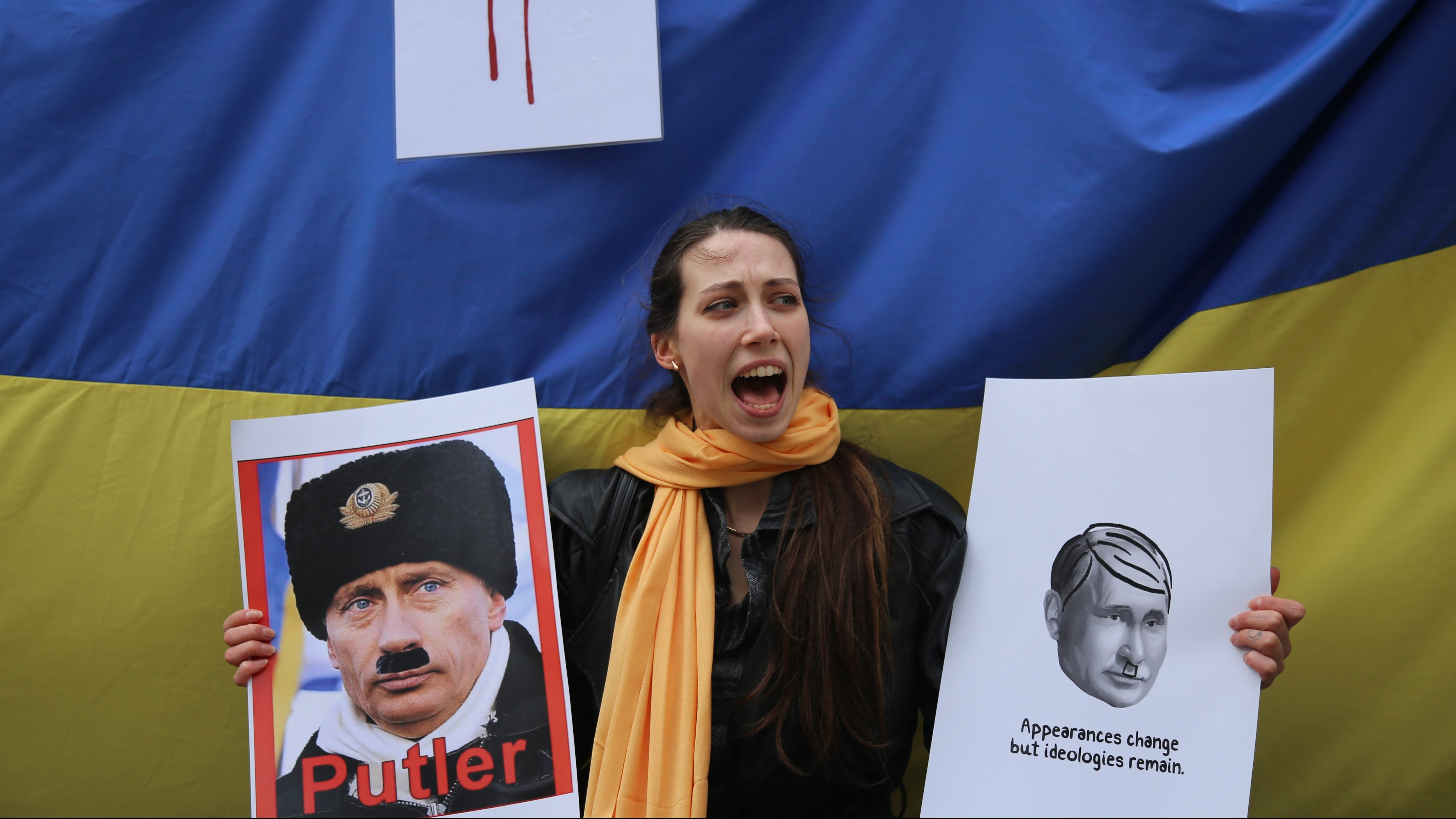ISTANBUL, TURKEY - 2022/02/28: A protester holds placards with a background of the Ukrainian flag during the demonstration against Russian aggression in Istanbul.On the fifth day of the attack of Russian military troops on Ukraine, Ukrainian citizens and anti-war demonstrators gathered in Istanbul to protest against Russia and Russian President Vladimir Putin. (Photo by Hakan Akgun/SOPA Images/LightRocket via Getty Images)
