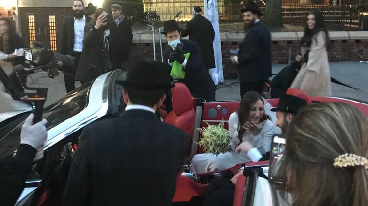 Groom JJ Deitch and wife, Fraida, ride in the pack of a convertible as People gather for their wedding in Brooklyn on March 19, 2020. - Once a run-of-the-mill soundtrack to New York's streets, in the time of a coronavirus a parade of cars honking their horns is a way to throw a socially distanced wedding reception. On the eve of a ban of all gatherings in the state battling the fast-spreading COVID-19, a handful of people gathered for a creative wedding in a pocket of Brooklyn populated by one of the borough's tight-knit Hasidic Jewish communities. (Photo by Maggy DONALDSON / AFP) (Photo by MAGGY DONALDSON/AFP via Getty Images)
