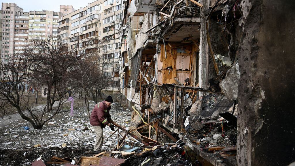 TOPSHOT - A man clears debris at a damaged residential building at Koshytsa Street, a suburb of the Ukrainian capital Kyiv, where a military shell allegedly hit, on February 25, 2022. - Russian forces reached the outskirts of Kyiv on Friday as Ukrainian President Volodymyr Zelensky said the invading troops were targeting civilians and explosions could be heard in the besieged capital. Pre-dawn blasts in Kyiv set off a second day of violence after Russian President Vladimir Putin defied Western warnings to unleash a full-scale ground invasion and air assault on Thursday that quickly claimed dozens of lives and displaced at least 100,000 people. (Photo by Daniel LEAL / AFP) (Photo by DANIEL LEAL/AFP via Getty Images)