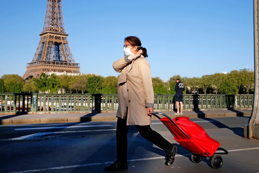 Una mujer utiliza una mascarilla mientras camina en París