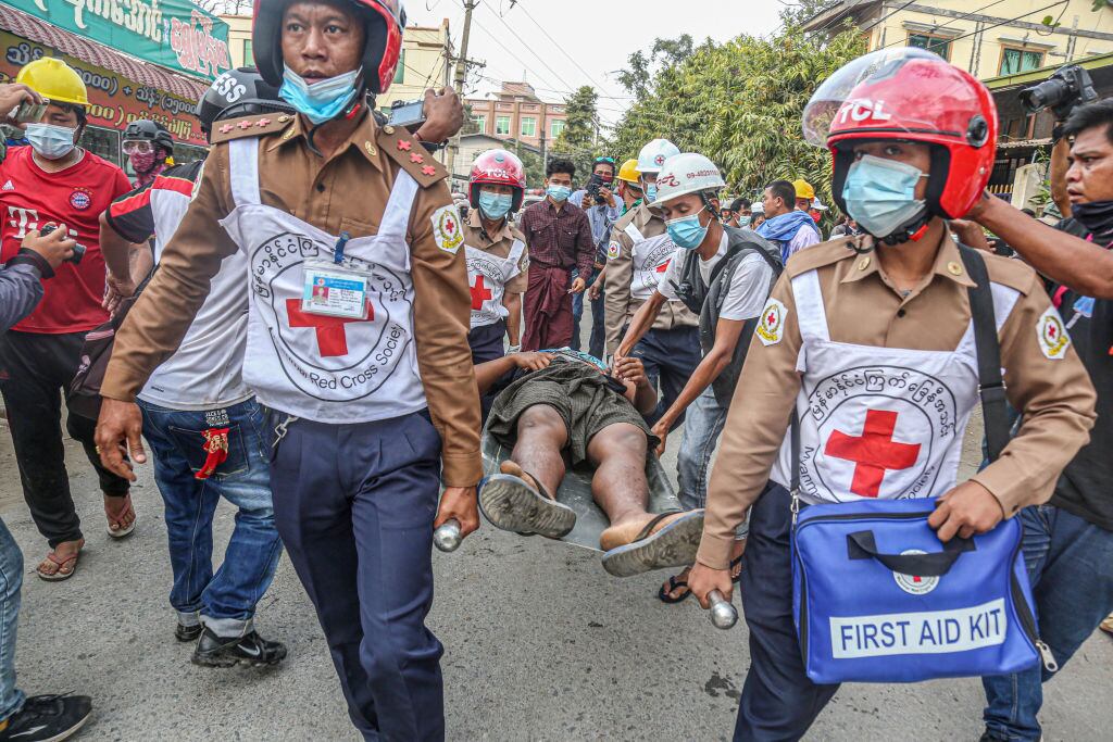 Asistentes transportan a un herido en medio de las manifestaciones en Mandalay
