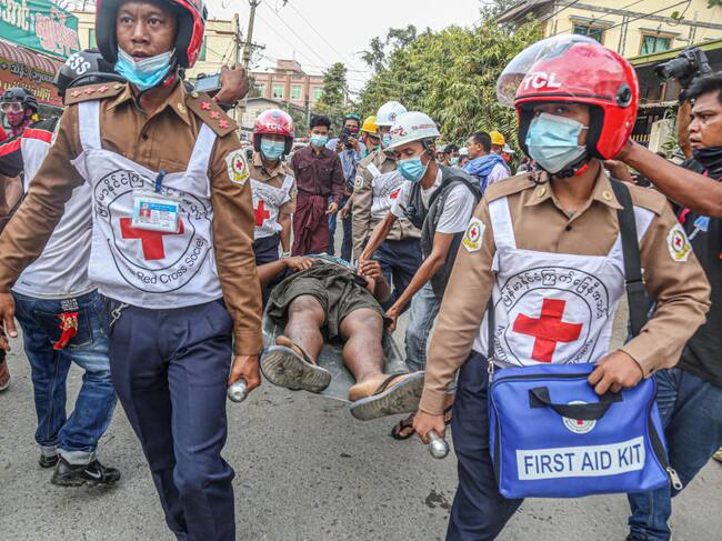 Asistentes transportan a un herido en medio de las manifestaciones en Mandalay