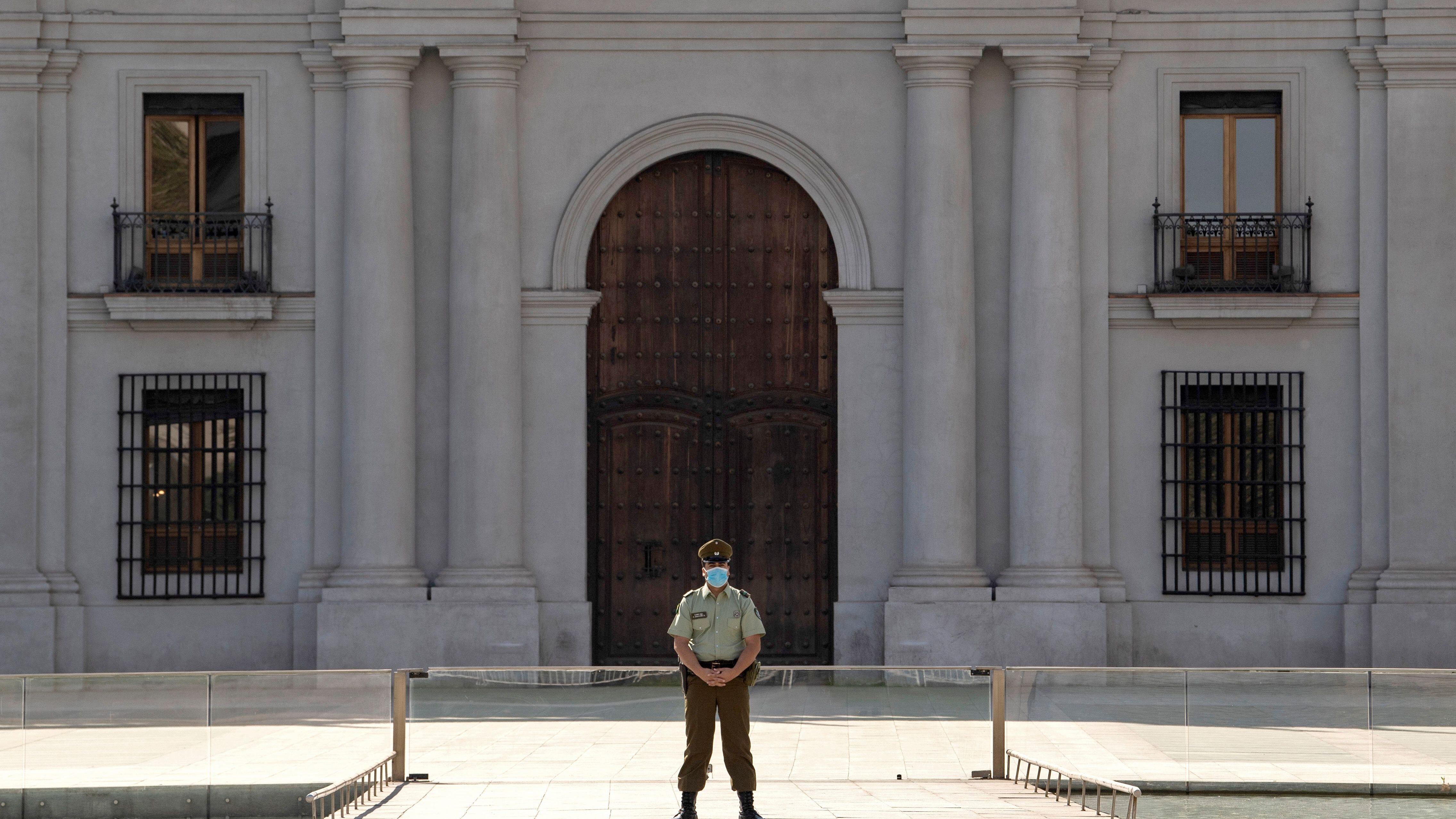 A police officer wears gloves and a face mask as he stands guard outside La Moneda presidential palace in Santiago, on April 09, 2020, amid the neew coronavirus pandemic. (Photo by MARTIN BERNETTI / AFP) (Photo by MARTIN BERNETTI/AFP via Getty Images)