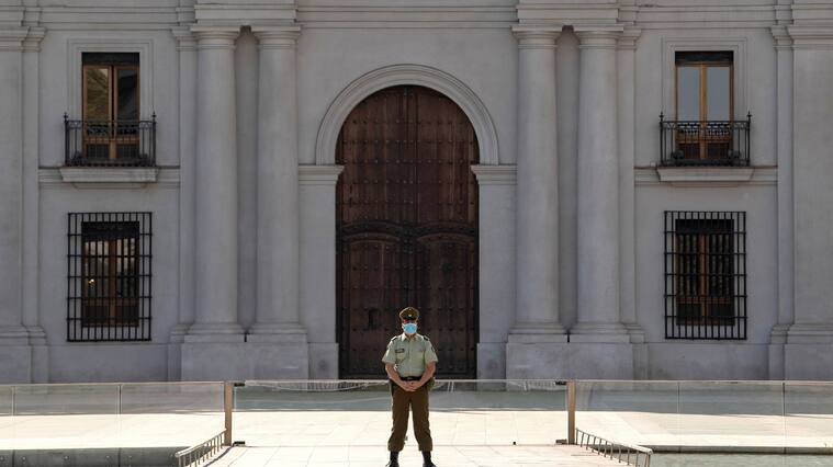 A police officer wears gloves and a face mask as he stands guard outside La Moneda presidential palace in Santiago, on April 09, 2020, amid the neew coronavirus pandemic. (Photo by MARTIN BERNETTI / AFP) (Photo by MARTIN BERNETTI/AFP via Getty Images)