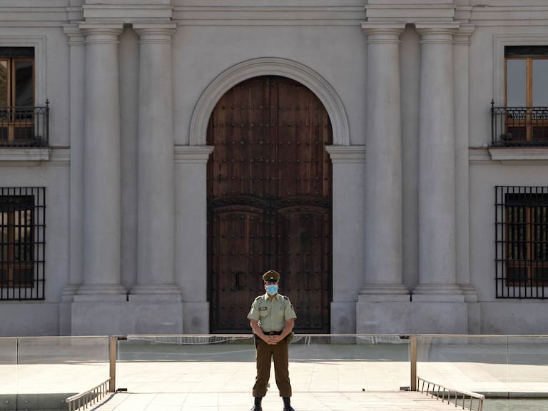 A police officer wears gloves and a face mask as he stands guard outside La Moneda presidential palace in Santiago, on April 09, 2020, amid the neew coronavirus pandemic. (Photo by MARTIN BERNETTI / AFP) (Photo by MARTIN BERNETTI/AFP via Getty Images)