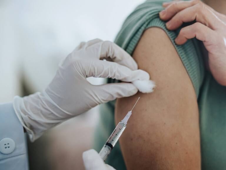 Close up of senior Asian woman getting Covid-19 vaccine in arm for Coronavirus immunization by a doctor at hospital. Elderly healthcare and illness prevention concept