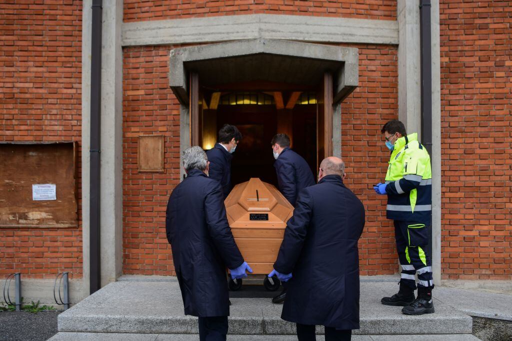 Empleados de una funeraria ingresan un féretro a una iglesia en la ciudad italiana de Bérgamo