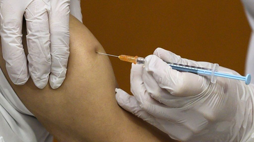 A medical worker (L) receives a dose of the Pfizer-BioNTech vaccine against the Covid-19 coronavirus as the country launches its inoculation campaign at the Tokyo National Hospital in Kiyose, Tokyo prefecture on February 17, 2021. (Photo by CHARLY TRIBALLEAU / AFP) (Photo by CHARLY TRIBALLEAU/AFP via Getty Images)