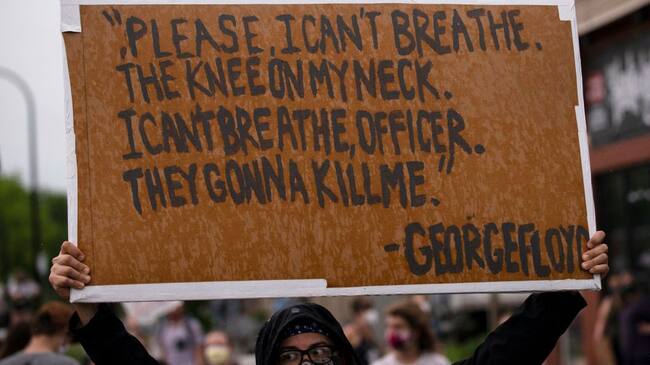 MINNEAPOLIS, MN - MAY 26: A protester holds a sign while demonstrating against the death of George Floyd outside the 3rd Precinct Police Precinct on May 26, 2020 in Minneapolis, Minnesota. Four Minneapolis police officers have been fired after a video taken by a bystander was posted on social media showing Floyd's neck being pinned to the ground by an officer as he repeatedly said, "I can’t breathe". Floyd was later pronounced dead while in police custody after being transported to Hennepin County Medical Center. (Photo by Stephen Maturen/Getty Images)