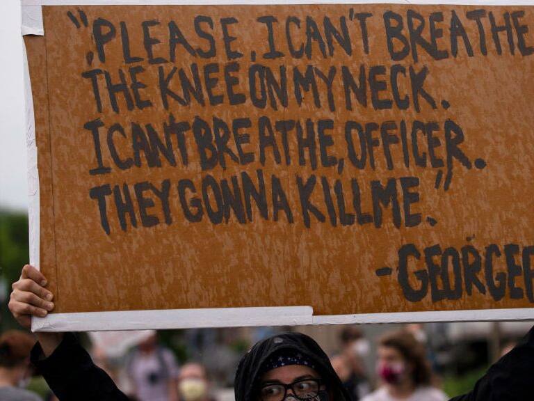 MINNEAPOLIS, MN - MAY 26: A protester holds a sign while demonstrating against the death of George Floyd outside the 3rd Precinct Police Precinct on May 26, 2020 in Minneapolis, Minnesota. Four Minneapolis police officers have been fired after a video taken by a bystander was posted on social media showing Floyd's neck being pinned to the ground by an officer as he repeatedly said, "I can’t breathe". Floyd was later pronounced dead while in police custody after being transported to Hennepin County Medical Center. (Photo by Stephen Maturen/Getty Images)