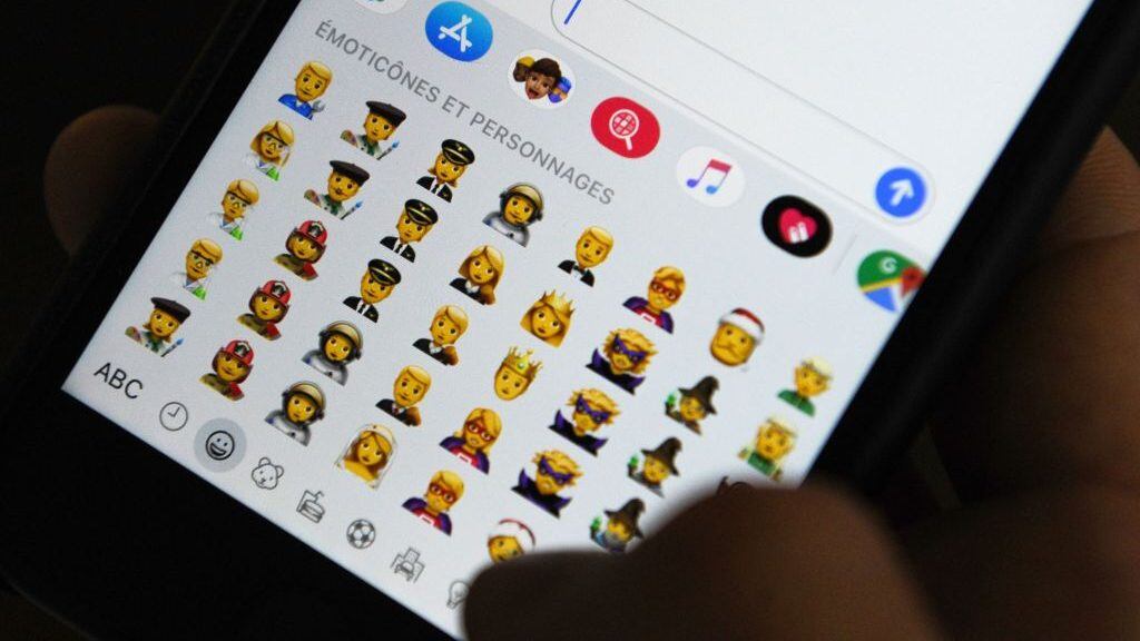 TOPSHOT - A person holds an iPhone showing emojis in Hong Kong, on October 30, 2019. - Apple has put out new gender neutral emojis of most of its people icons -- including punks, clowns and zombies -- as part of an update to its mobile operating system.The tech giant has offered growing numbers of inclusive designs in recent years, putting out a range of skin tones and occupations, with Google's Android publishing its own non-binary faces in May. (Photo by TENGKU Bahar / AFP) (Photo by TENGKU BAHAR/AFP via Getty Images)