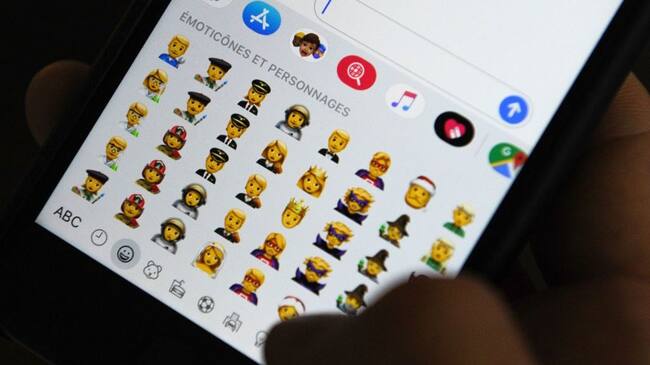 TOPSHOT - A person holds an iPhone showing emojis in Hong Kong, on October 30, 2019. - Apple has put out new gender neutral emojis of most of its people icons -- including punks, clowns and zombies -- as part of an update to its mobile operating system.The tech giant has offered growing numbers of inclusive designs in recent years, putting out a range of skin tones and occupations, with Google's Android publishing its own non-binary faces in May. (Photo by TENGKU Bahar / AFP) (Photo by TENGKU BAHAR/AFP via Getty Images)