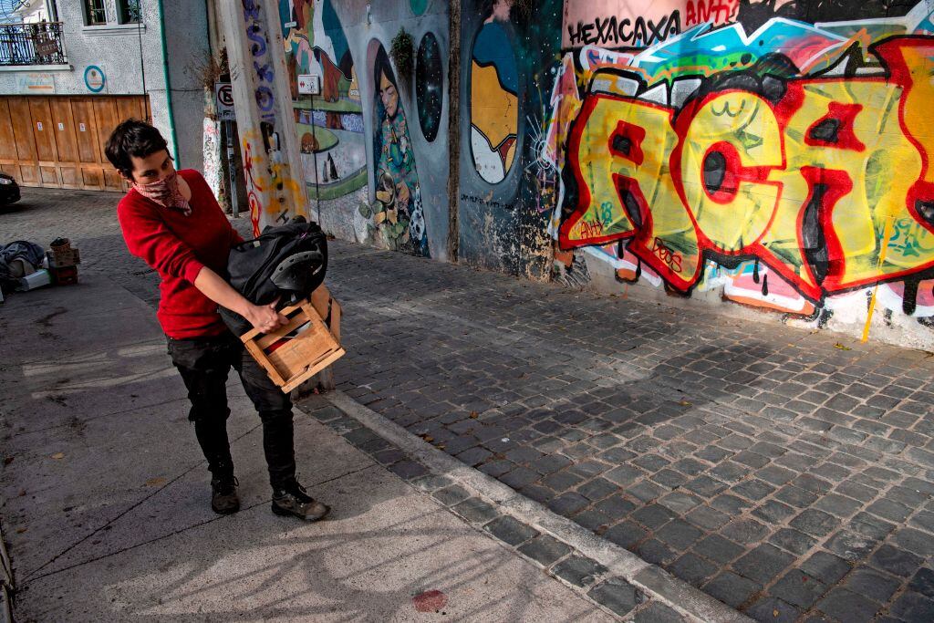 A woman carries a box as she walks up a hill since elevators are currently out of operation due to the new coronavirus pandemic, in Valparaiso, Chile, on June 08, 2020. - Amid the hills of Valparaiso, the new coronavirus advances and intimidates a port city without tourists or lifts to the slopes, which residents need to walk up and down carrying groceries to get home. (Photo by MARTIN BERNETTI / AFP) (Photo by MARTIN BERNETTI/AFP via Getty Images)