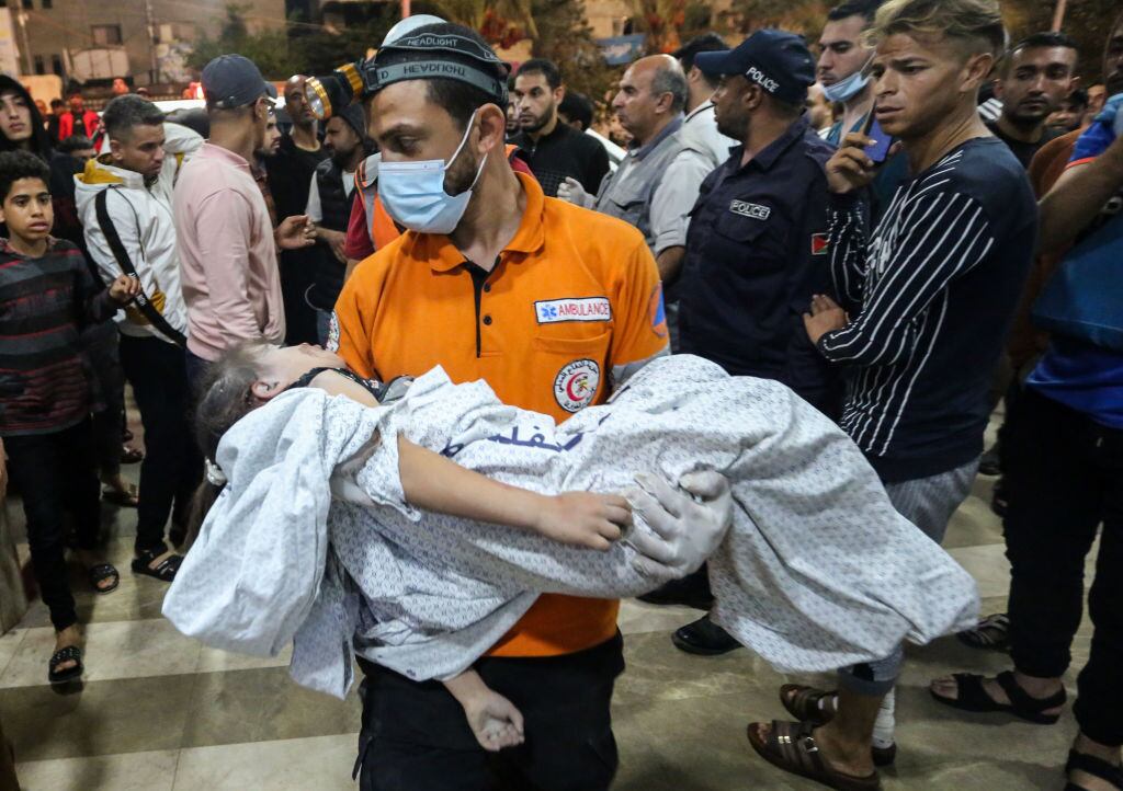 Paramédico lleva un niño herido por bombardeos de Israel contra Gaza