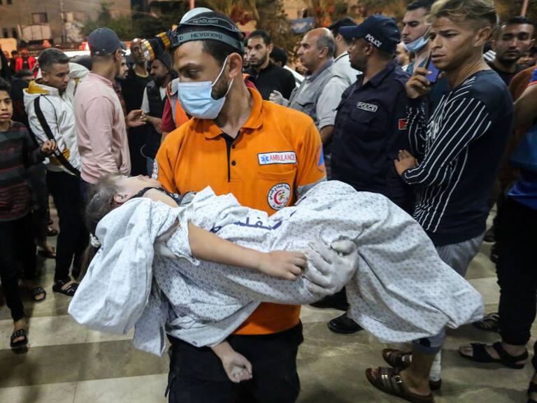 Paramédico lleva un niño herido por bombardeos de Israel contra Gaza
