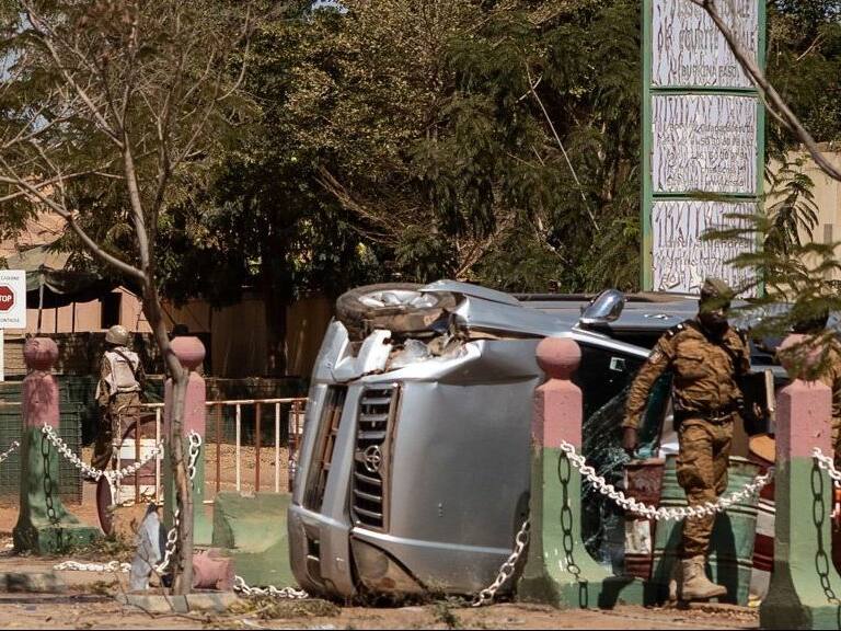 Burkina Faso soldiers stand by a damaged vehicle in front of the Guillaume Ouedraogo military camp in Ouagadougou on January 24, 2022. - Mutinous troops in Burkina Faso arrested and detained President Roch Marc Christian Kabore and his ministers on January 24, 2022, demanding more resources for the battle against Islamist insurgents, security sources told AFP.The arrests came a day after soldiers at several barracks across the volatile West African country staged an uprising over the government's handling of the jihadist threat. (Photo by OLYMPIA DE MAISMONT / AFP) (Photo by OLYMPIA DE MAISMONT/AFP via Getty Images)