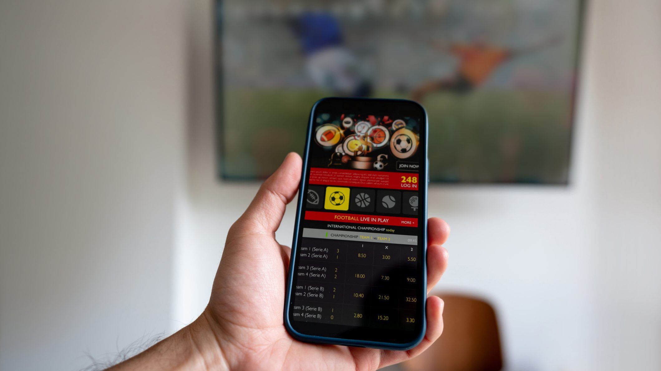 Man watching a football match and gambling on a mobile app - sports betting concepts. **DESIGN ON BOTH SCREENS WERE MADE FROM SCRATCH BY US**