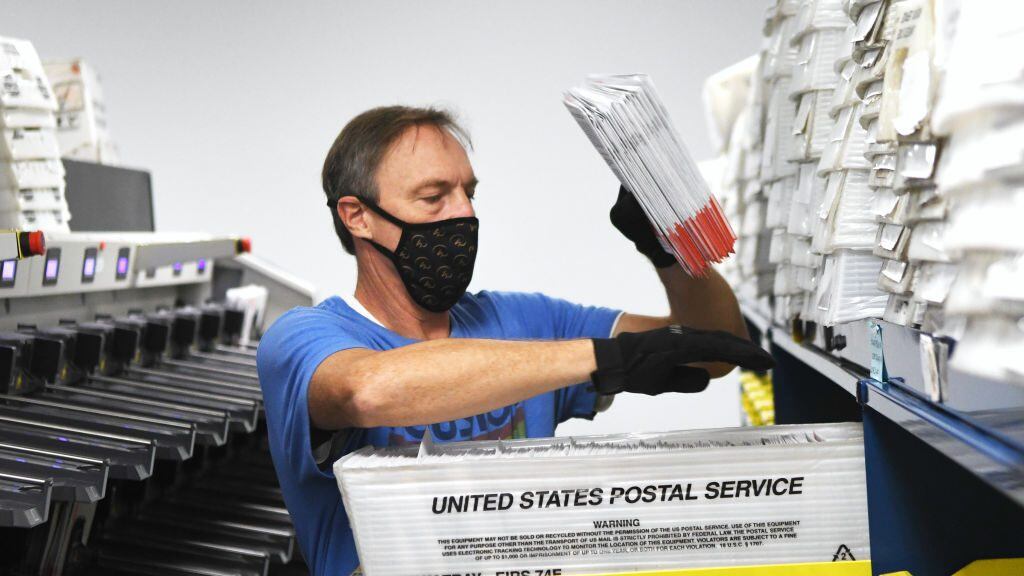 Michael Duve places mail-in ballots into trays in the sorting room at the Orange County Supervisor of Elections office on October 26, 2020 in Orlando, Florida. With nine days until the November 3 election, more people already have cast ballots in this years presidential election than voted early or absentee in the 2016 race.  (Photo by Paul Hennessy/NurPhoto via Getty Images)