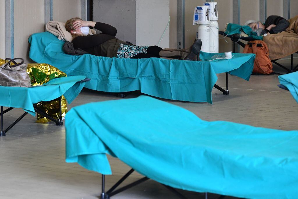 Patients lie in bed at a temporary emergency structure set up outside the accident and emergency department, where any new arrivals presenting suspect new coronavirus symptoms will be tested, at the Brescia hospital, Lombardy, on March 13, 2020. (Photo by Miguel MEDINA / AFP) (Photo by MIGUEL MEDINA/AFP via Getty Images)