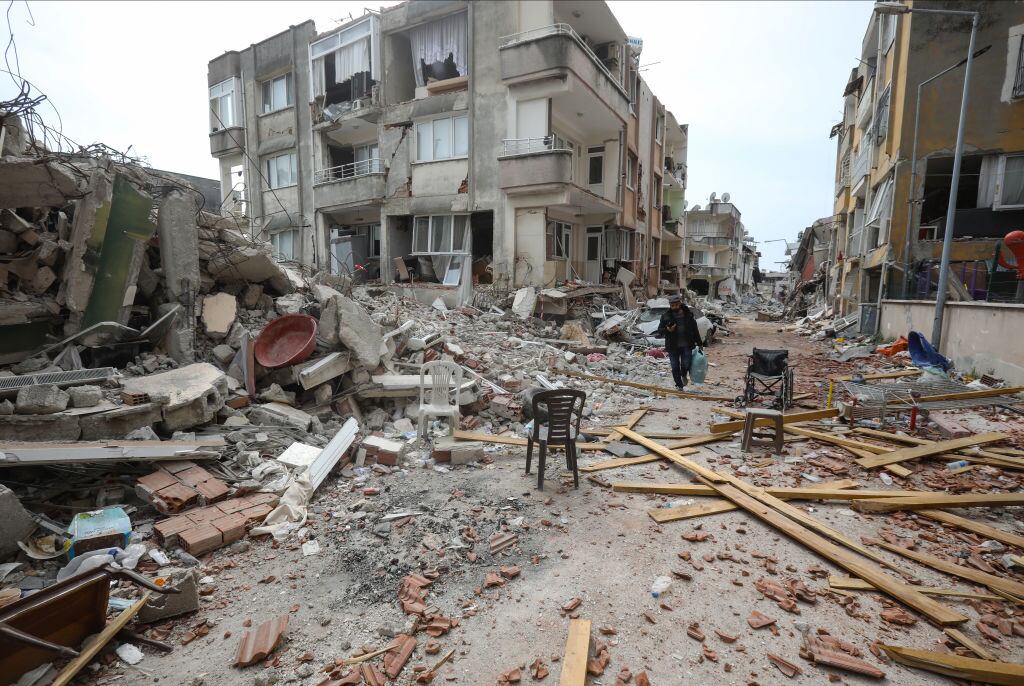 Personas caminan entre los escombros que dejaron los terremotos en Turquía