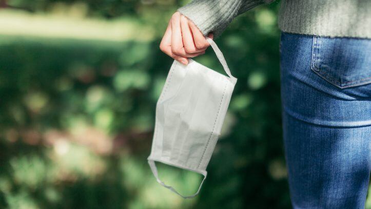 Cropped shot of the rear view of a woman taking off her protective face mask while walking at the park, enjoying a virus-free zone when coronavirus has ended.