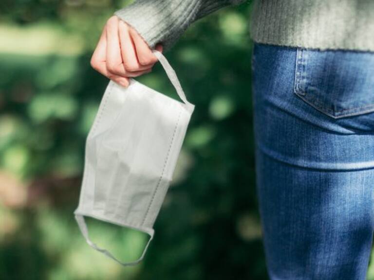 Cropped shot of the rear view of a woman taking off her protective face mask while walking at the park, enjoying a virus-free zone when coronavirus has ended.