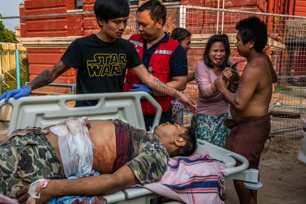 Personas observan a un herido por la represión en Myanmar