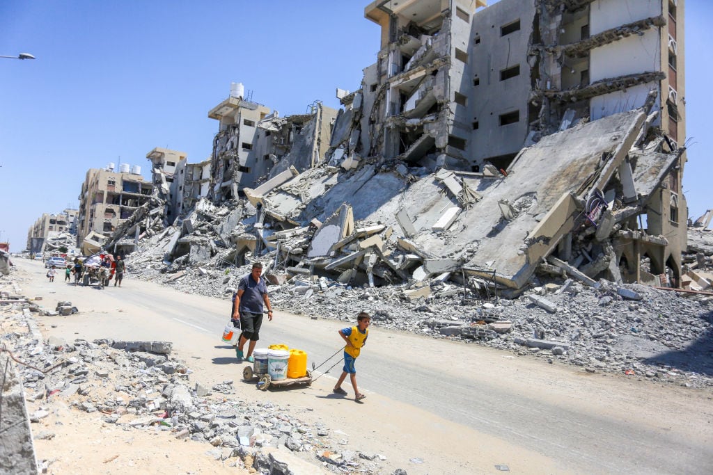 Familias caminan en medio de la destrucción en la Franja de Gaza tras la serie de ataques militares de Israel en contra del territorio de Palestina.